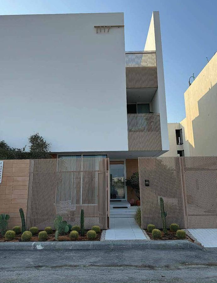 Completed private residence facade with a timber-slat gate and desert planting in Al Khobar